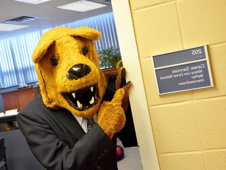 Nittany Lion in a suit pointing at Career Services office sign